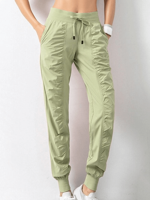 Green women's sports joggers with side pockets, cuffs, and a drawstring waist. Comfortable, stylish, and perfect for casual wear.